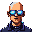 Close-up portrait of a bald individual with a goatee wearing futuristic blue-tinted glasses. The character has a subtle icy sheen on their glasses and wears a dark, collared garment with pixelated detailing.