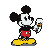 Mickey Mouse in red shorts and yellow shoes happily eating an ice cream cone.