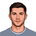 Young man with short dark hair, stubble, and a serious expression, wearing a light grey t-shirt.