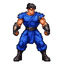 A muscular fighter with dark hair and a stern expression wears a vibrant blue outfit, including a short-sleeved tunic, sash, loose pants, boots, and black fingerless gloves.