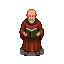 A bald monk with a white beard, wearing a brown robe, holds an open holy book.